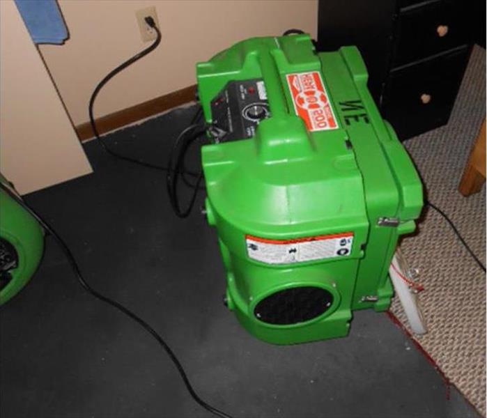 green air scrubber on a carpet with part of an air mover in the photo
