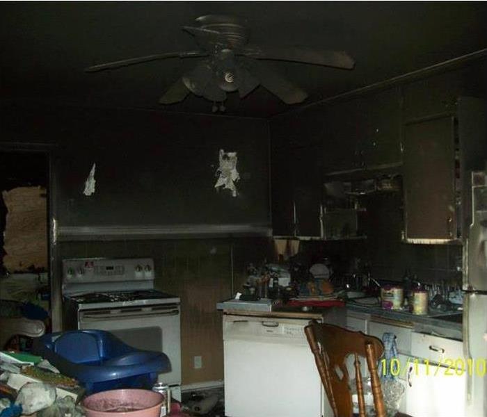 Kitchen with appliances and extensive fire damage around walls and ceiling fan