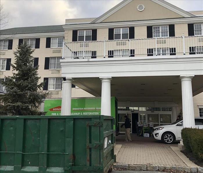 A Hotel with a SERVPRO truck and a dumpster in front after storm damage.