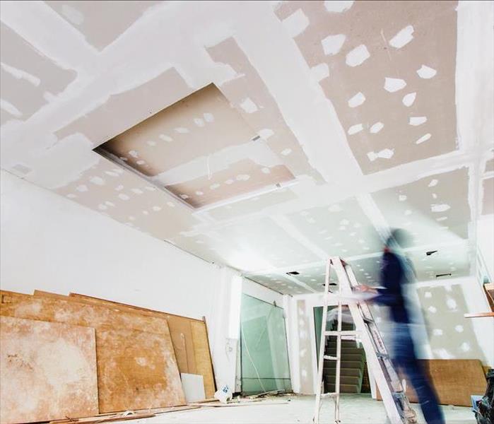 A worker installs drywall in a construction project.