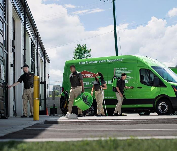 SERVPRO Employees moving equipment from a van into a building.